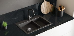 Top view of black marble kitchen sink standing on white countertop in room with black walls. Wooden round cutting board and little potted plant. 3d rendering